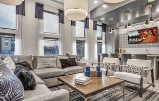 A modern living room with a grey sofa, a wooden coffee table, and a large painting on the wall.