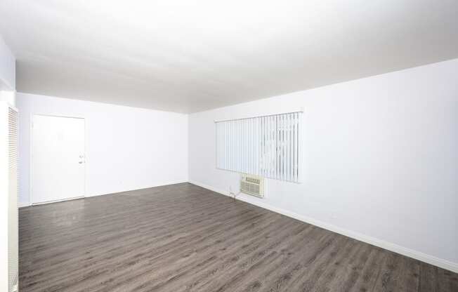 an empty room with white walls and wood floors