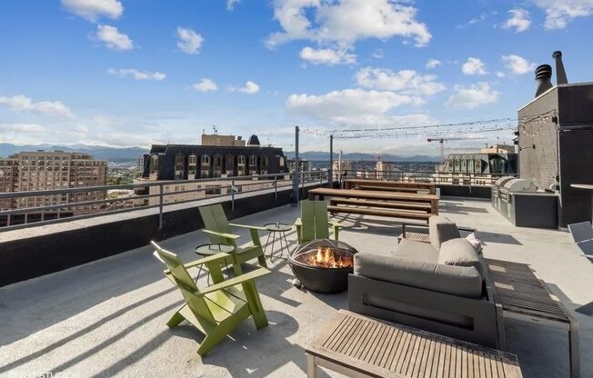 A rooftop patio with a fire pit and seating area at Archer Tower in Denver, CO