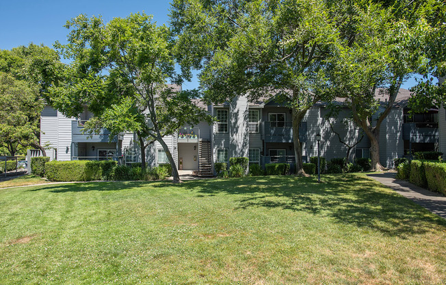 A grassy area in front of a building with trees at Rocklin Gold Apartments, California, 95677