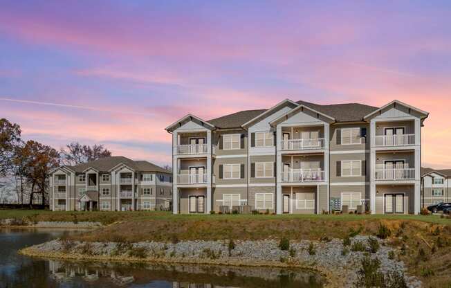 Rear of an apartment building with private balconies by a pond at The Alexandria in Madison, AL