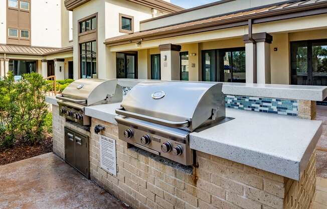 a large stainless steel grill sits on a stone counter outside of a building