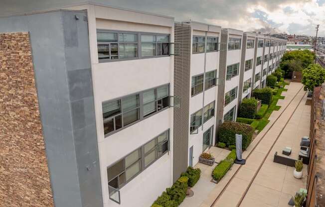A modern apartment building with a brick wall on the left side and a well-maintained lawn in front.