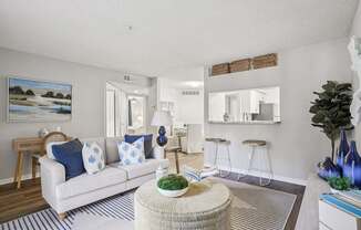 A living room with a white couch and a painting on the wall.