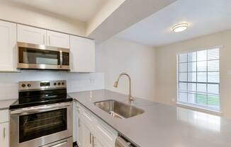 a kitchen with white cabinets and stainless steel appliances