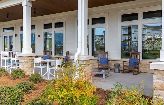 A white house with a porch and blue chairs.