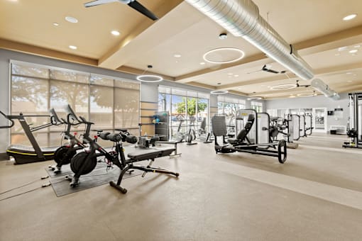 a gym with weights and other exercise equipment in a building with large windows