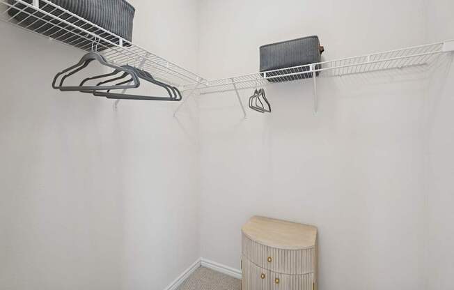 A white closet with a shelf and a round stool.