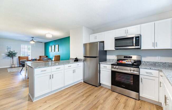 A kitchen with white cabinets and a stainless steel refrigerator.