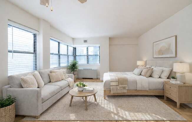A well-lit bedroom with a large bed, a couch, and a coffee table.