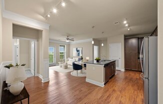 A well-lit kitchen with a refrigerator, sink, and dining table.