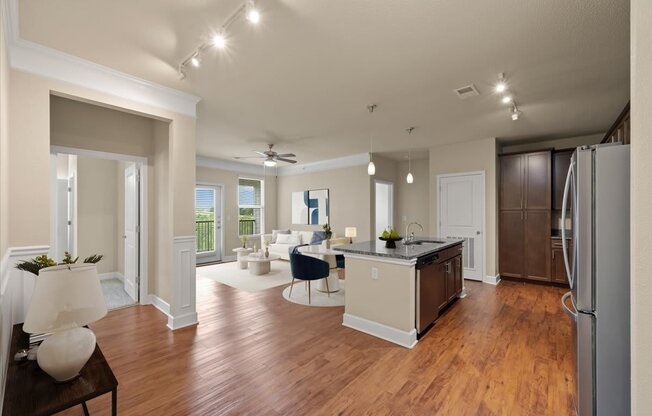 A well-lit kitchen with a refrigerator, sink, and dining table.
