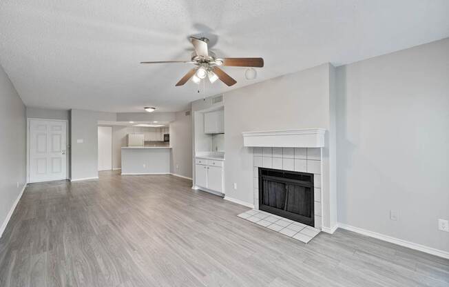 A spacious living room with a fireplace and a ceiling fan.