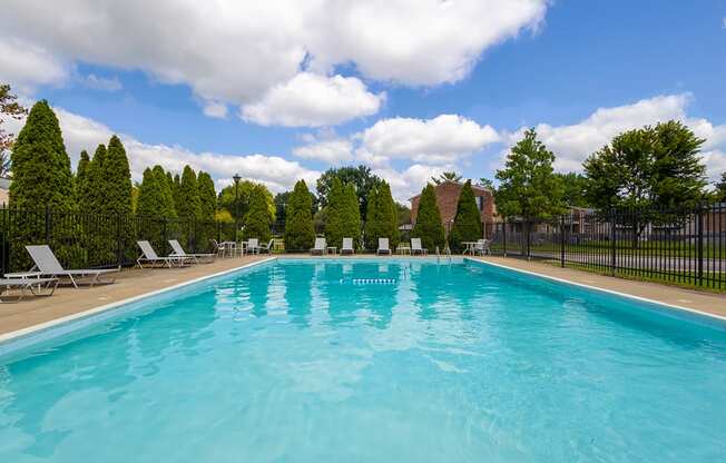 A large swimming pool surrounded by trees and lounge chairs.