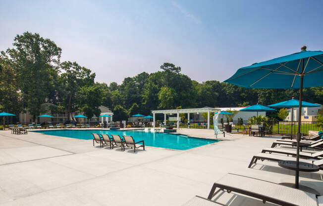 a swimming pool with lounge chairs and umbrellas