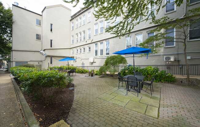 a patio with tables and umbrellas in a courtyard