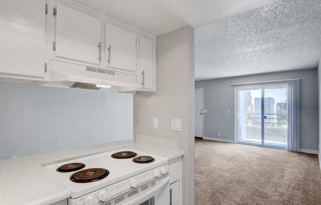 an empty kitchen with white appliances and a door to a balcony