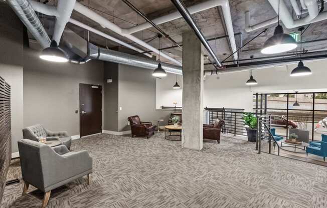 a lobby with couches and chairs in a building with exposed ceilings