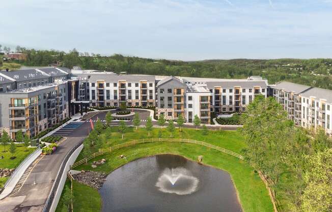 an aerial view of a building with a fountain in the middle of a pond