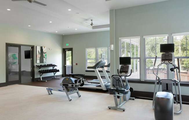 A gym with a variety of equipment including a treadmill, weights, and a bench press.