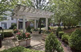 A garden with a white pergola and a brick pathway.