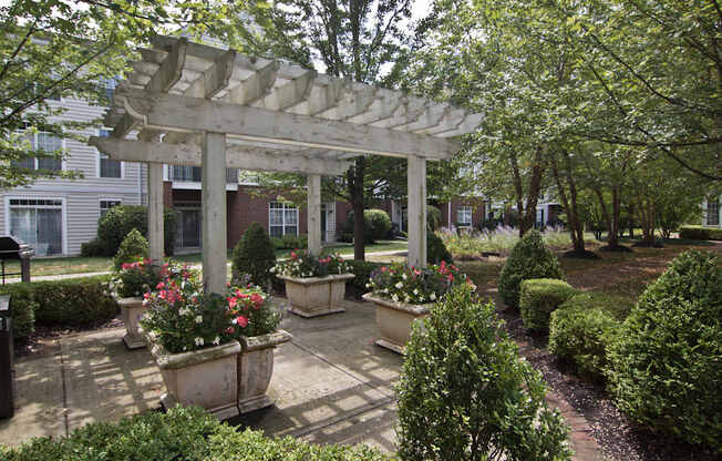 A garden with a white pergola and a brick pathway.