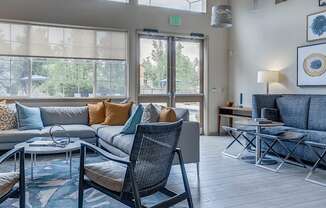 A living room with a grey couch, a black chair, and a glass table.