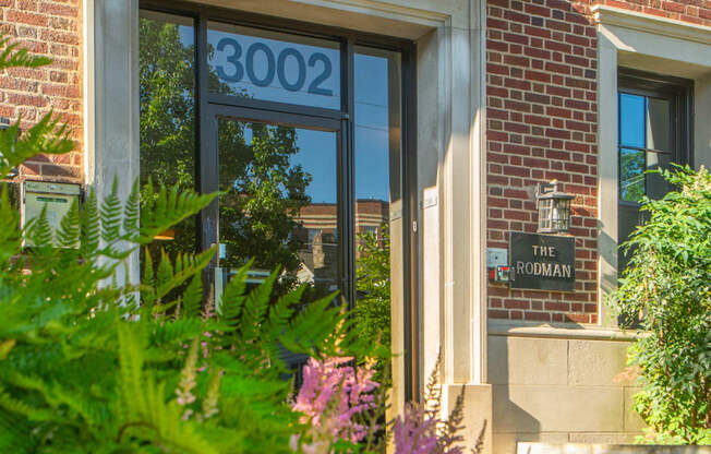 the front door of a brick building with flowers in front of it