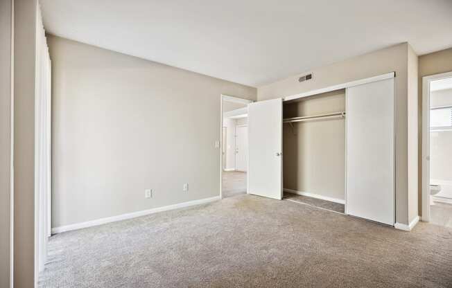 an empty living room with an open door to a closet