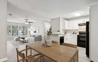 Model Dining Room with Wood-Style Flooring and View of Kitchen/Living Room at Huntington Place Apartments located in Sarasota, FL.