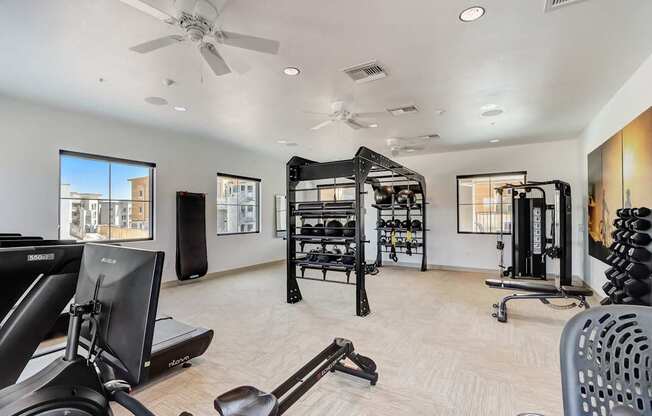 A spacious home gym with a variety of equipment including treadmills, weights, and a television.