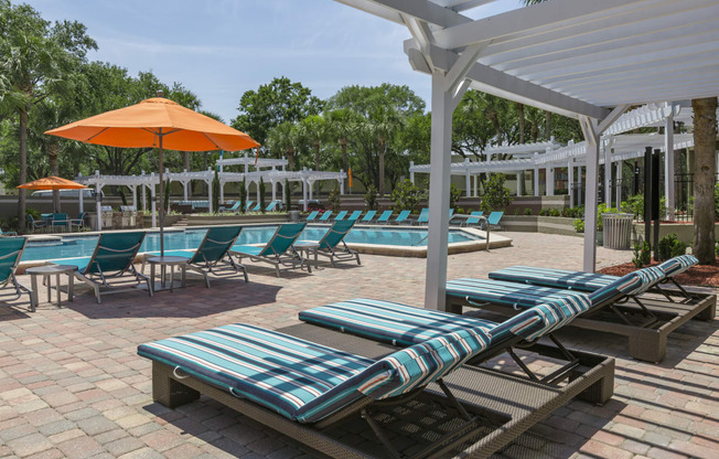 a pool area with lounge chairs and umbrellas