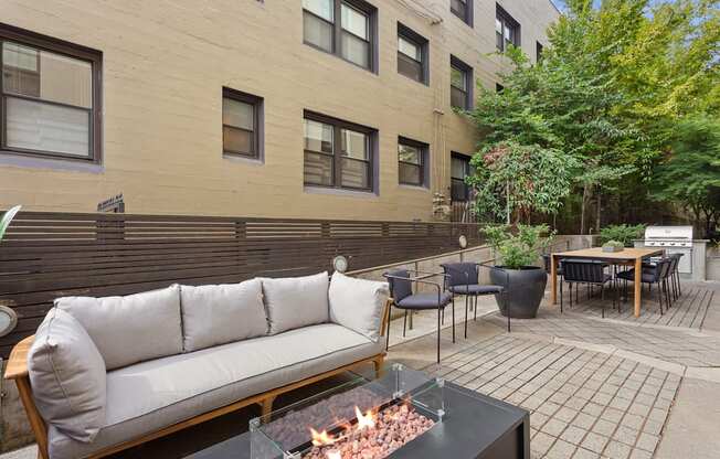 a patio with a couch and tables and a fire pit