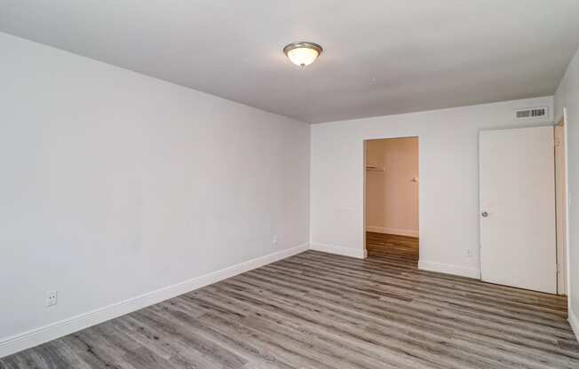 a bedroom with hardwood floors and white walls