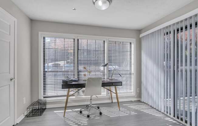 a home office with blinds on the windows and a desk with a chair