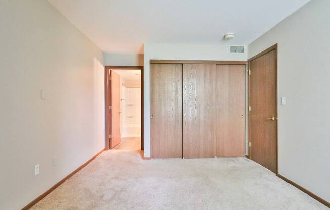 A room with a carpeted floor and two wooden doors.