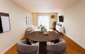 A round wooden table with four grey chairs in a room.