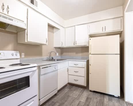 A white kitchen with a stove, sink, and refrigerator.