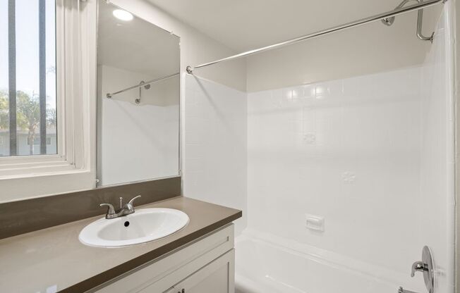 A white bathroom with a sink and a shower.