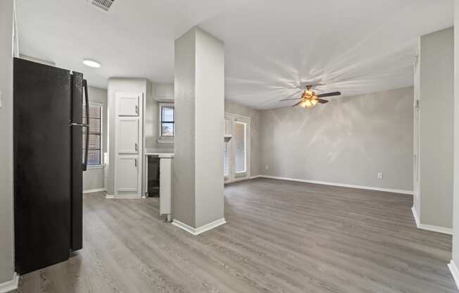 an empty living room and kitchen with a ceiling fan