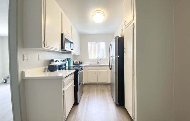 a kitchen with white cabinets and a black refrigerator