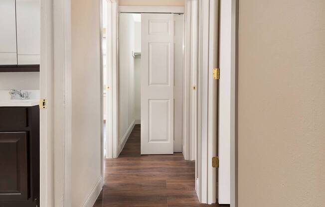 A long hallway with white doors and brown floors.