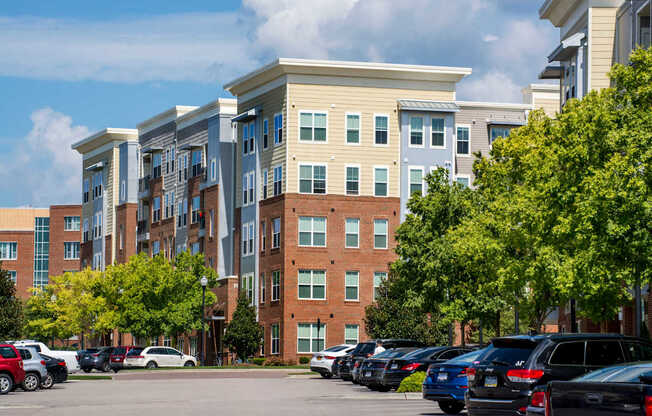 A parking lot with cars and apartment buildings in the background.
