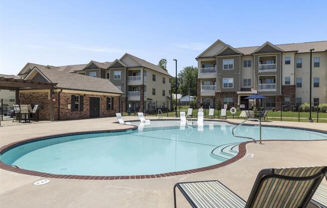 a swimming pool with an apartment building in the background at The Maddox Apartments, Centerton, AR