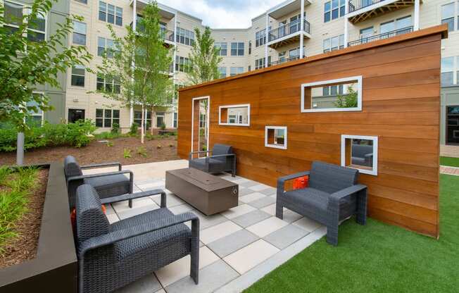 a backyard patio with chairs and a wooden shed