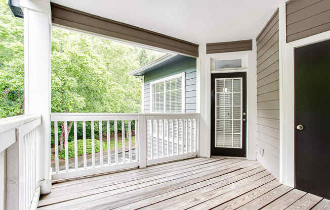 a covered balcony at avenues of kennesaw with a door and trees in the background