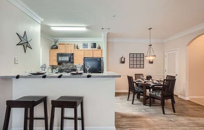 a kitchen with a bar and a dining room with a table