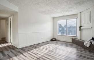 an empty living room with wood floors and a window