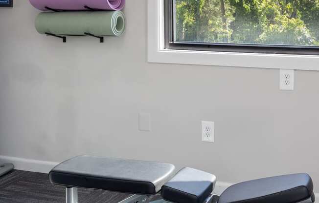 a gym with two chairs and a reformer in front of a window