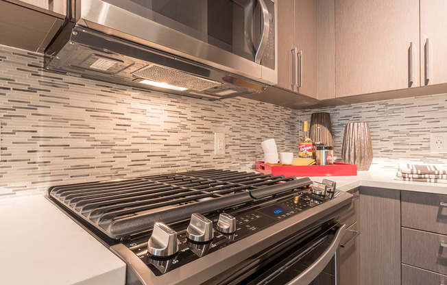 Designer inspired backsplash, under cabinet lighting and gas cooktops